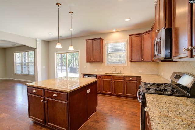 kitchen featuring arched walkways, stainless steel appliances, dark wood-type flooring, a kitchen island, and a sink