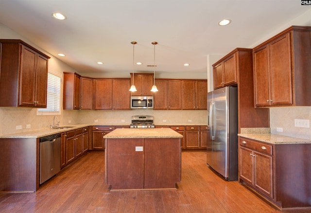 kitchen with dark wood finished floors, stainless steel appliances, a sink, and a center island