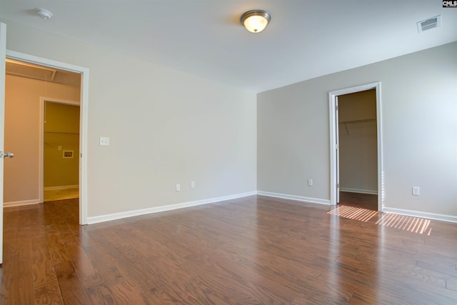 unfurnished room with visible vents, wood finished floors, attic access, and baseboards