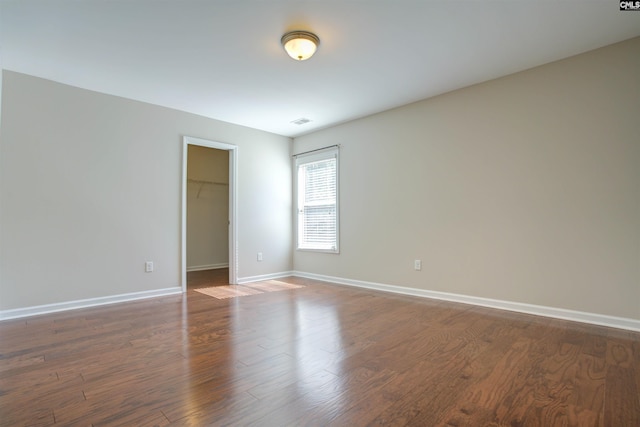 spare room featuring wood finished floors, visible vents, and baseboards