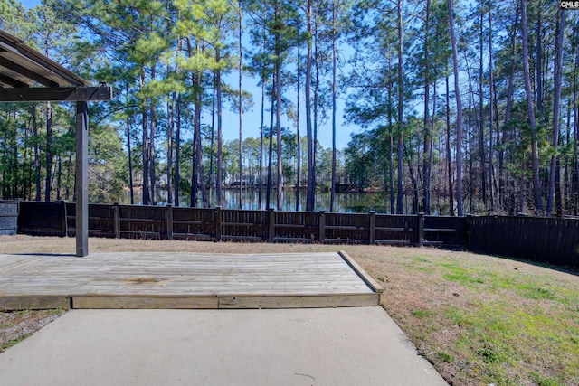 view of yard with a fenced backyard and a deck with water view