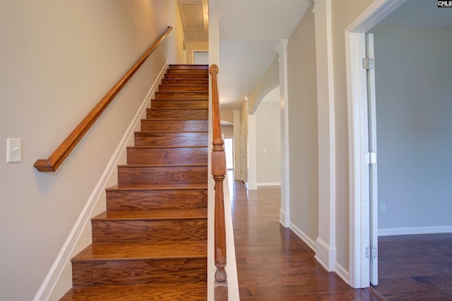 stairway with arched walkways, baseboards, and wood finished floors