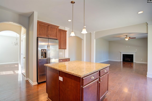 kitchen featuring arched walkways, ceiling fan, dark wood-type flooring, stainless steel fridge with ice dispenser, and a center island