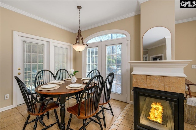 dining space featuring light tile patterned floors, baseboards, ornamental molding, and a tile fireplace