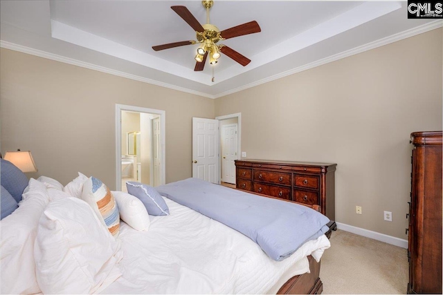 bedroom featuring baseboards, a tray ceiling, ensuite bath, and light colored carpet