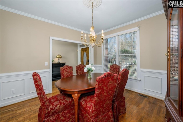 dining space featuring crown molding, dark wood-style flooring, visible vents, and a notable chandelier