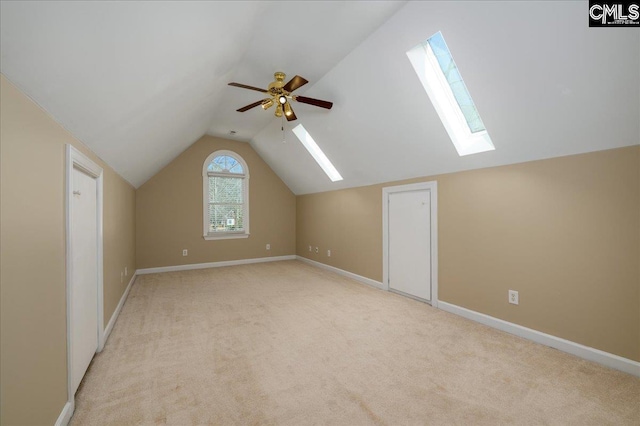 bonus room featuring light carpet, lofted ceiling with skylight, baseboards, and a ceiling fan