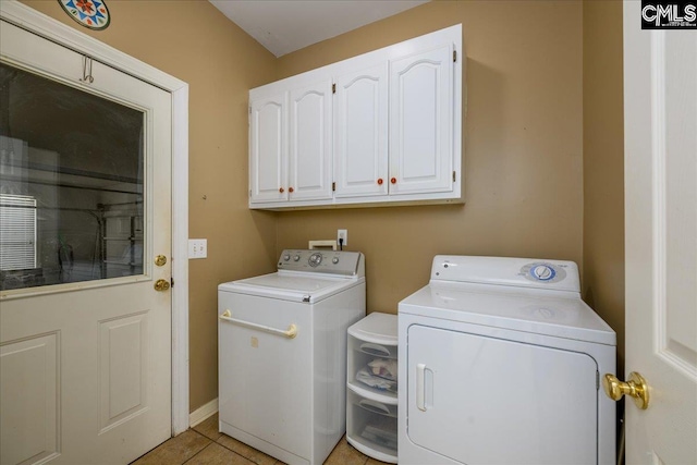 clothes washing area with light tile patterned floors, independent washer and dryer, and cabinet space