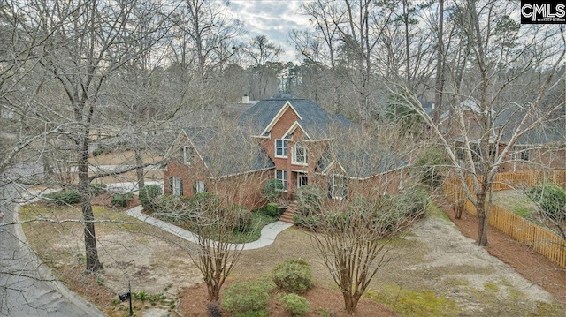 view of front of house with brick siding, fence, and roof with shingles