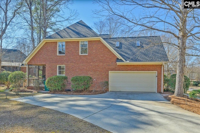 view of side of property featuring a shingled roof, brick siding, driveway, and a garage