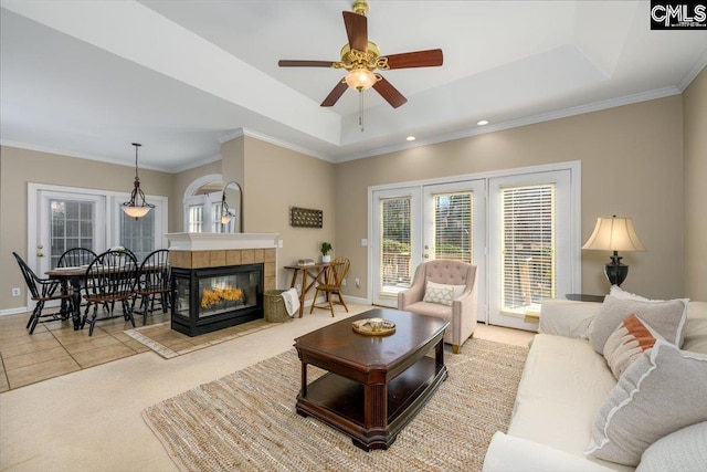 living room featuring a fireplace, baseboards, a raised ceiling, and crown molding