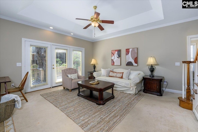 living area featuring a raised ceiling, light colored carpet, and plenty of natural light