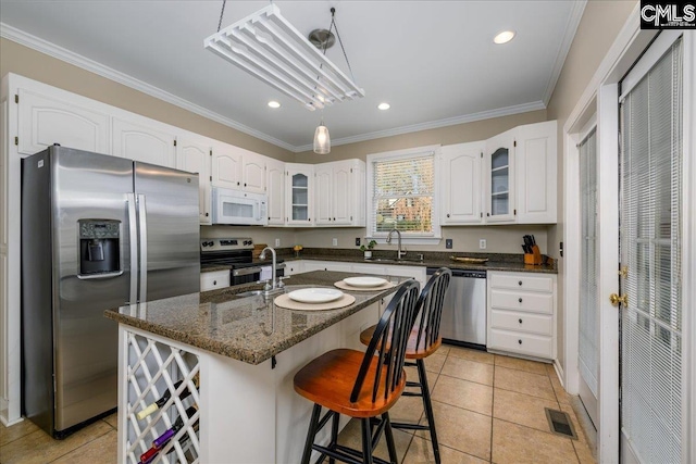 kitchen featuring stainless steel appliances, visible vents, ornamental molding, white cabinets, and a sink