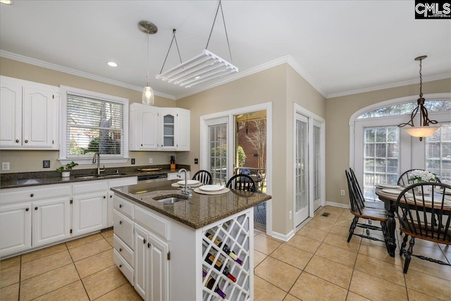 kitchen featuring crown molding, dark stone counters, and a sink