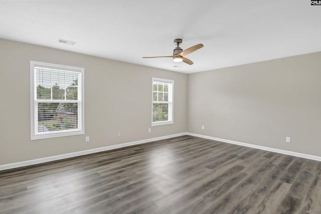 spare room with ceiling fan, baseboards, visible vents, and dark wood finished floors