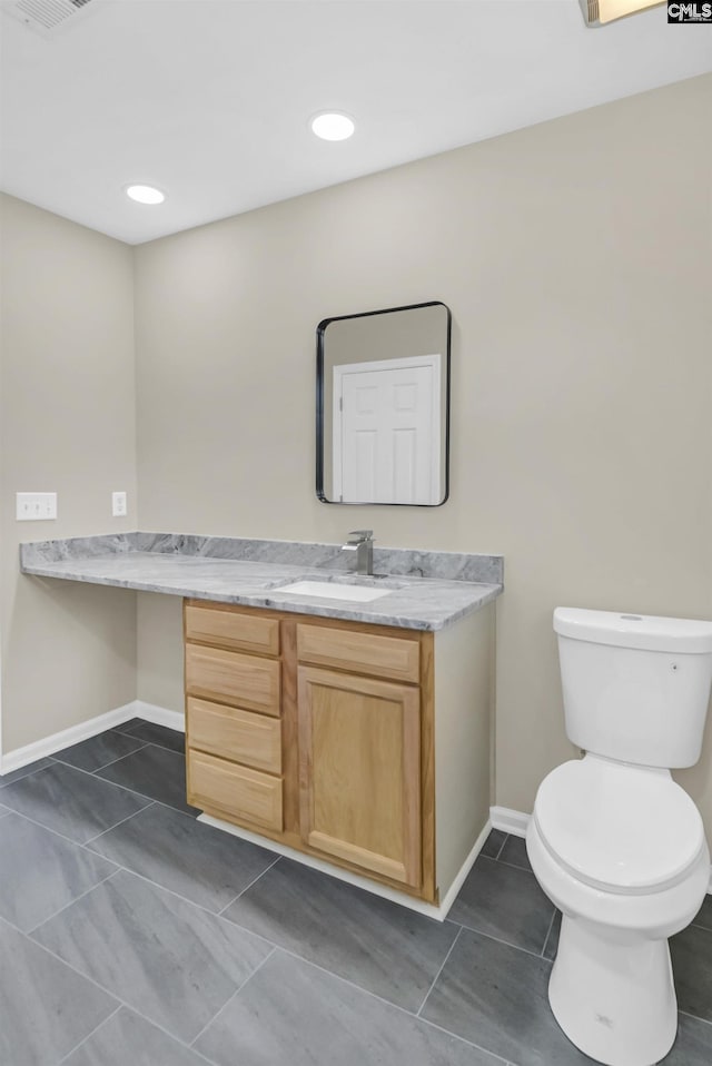 half bathroom featuring baseboards, toilet, tile patterned floors, vanity, and recessed lighting