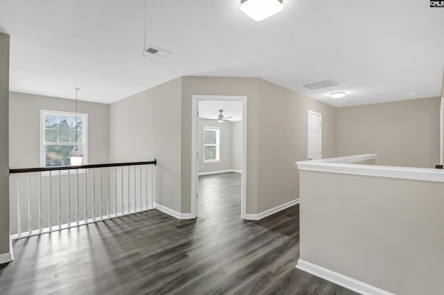 hallway featuring an upstairs landing, visible vents, dark wood finished floors, and baseboards