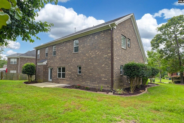 rear view of house featuring a yard, brick siding, a patio area, and fence