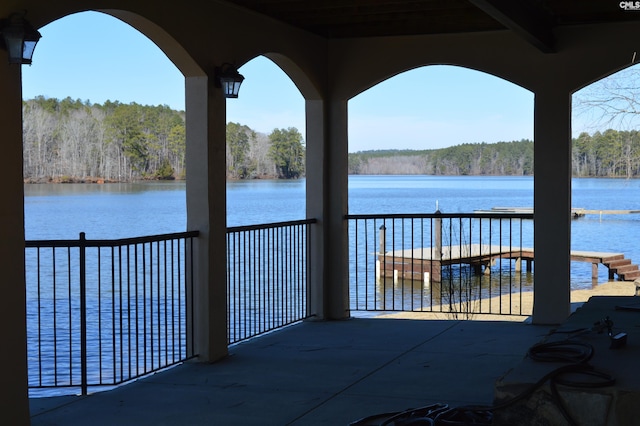 view of patio with a water view, a balcony, and a view of trees