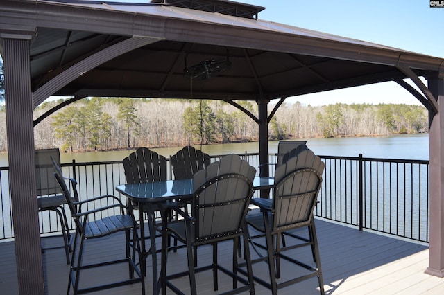 wooden terrace with a water view, outdoor dining area, and a gazebo