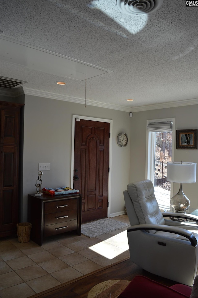 living room featuring attic access, visible vents, a textured ceiling, and ornamental molding