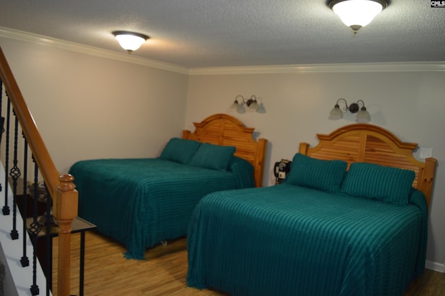 bedroom with a textured ceiling, wood finished floors, and crown molding