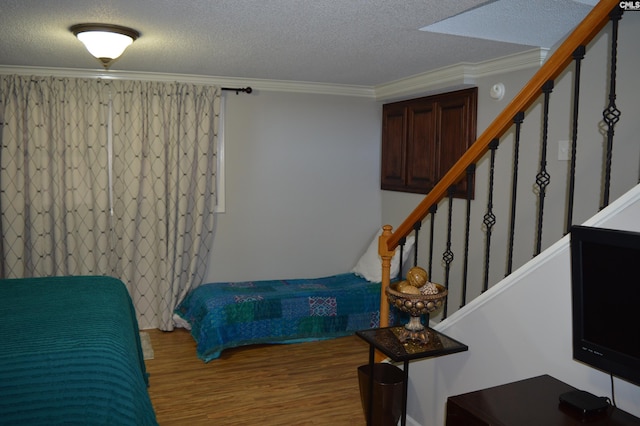 bedroom featuring ornamental molding, a textured ceiling, and wood finished floors