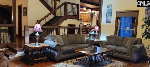 living room featuring a notable chandelier, stairway, and wood finished floors