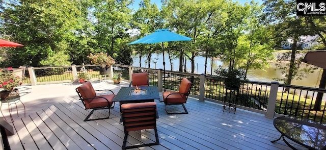 wooden terrace featuring a fire pit and a water view