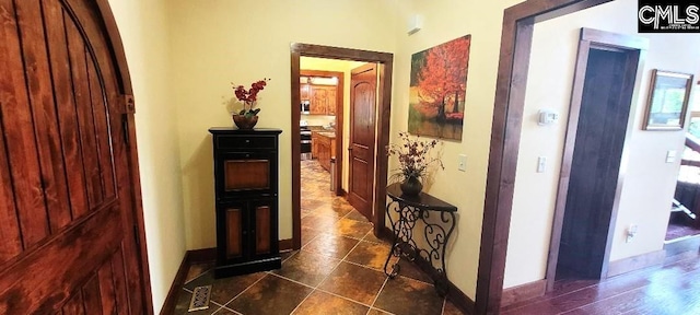 corridor with dark tile patterned floors and baseboards