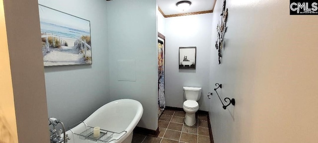 bathroom featuring toilet, a freestanding tub, baseboards, and tile patterned floors