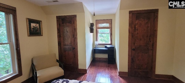 hall with dark wood-type flooring, visible vents, and baseboards