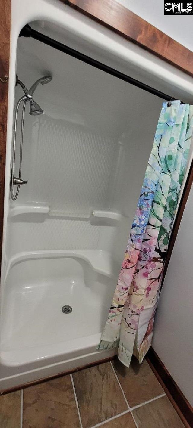 full bath with a shower with curtain, baseboards, and tile patterned floors