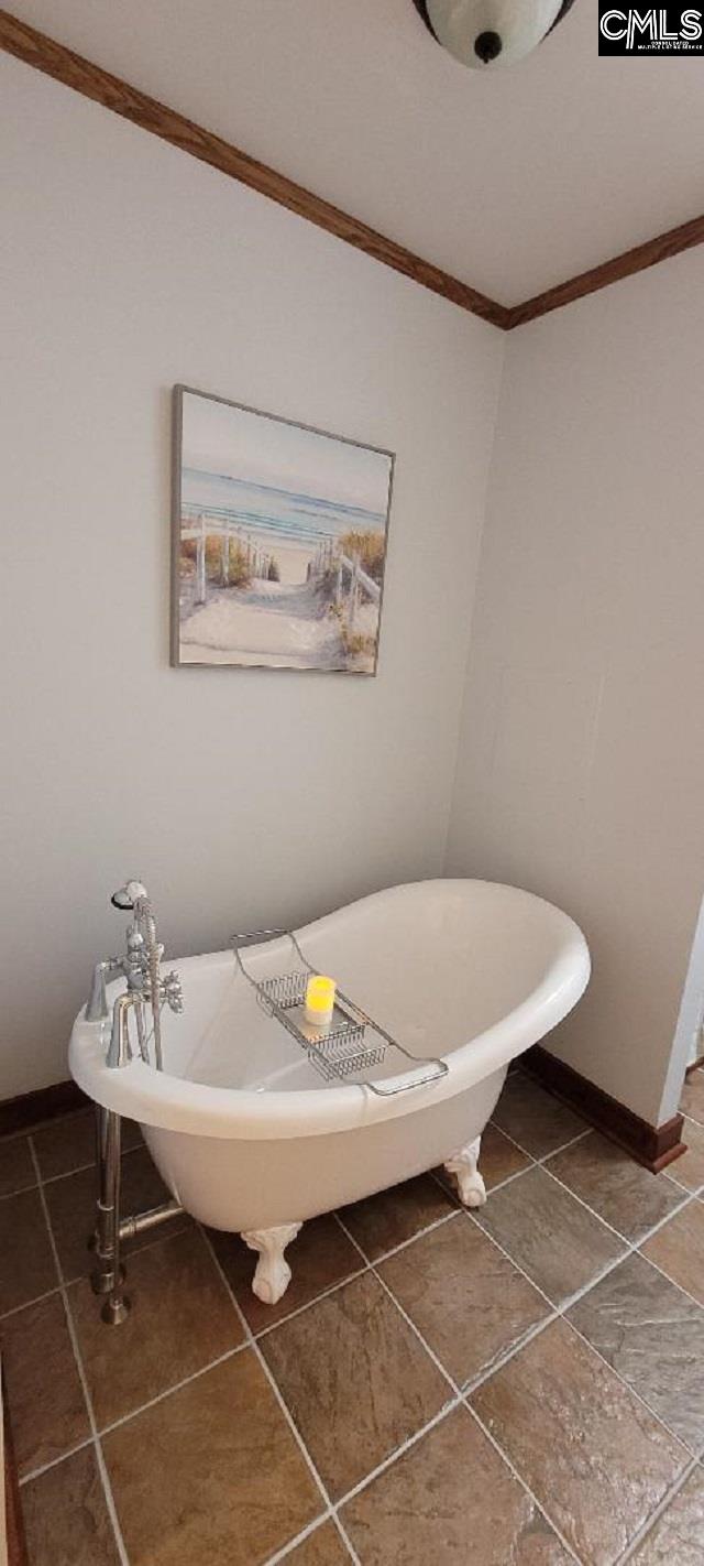 bathroom with a freestanding tub, baseboards, crown molding, and tile patterned floors