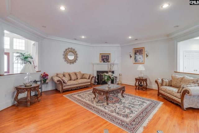 living area with light wood-type flooring, recessed lighting, a fireplace, and crown molding