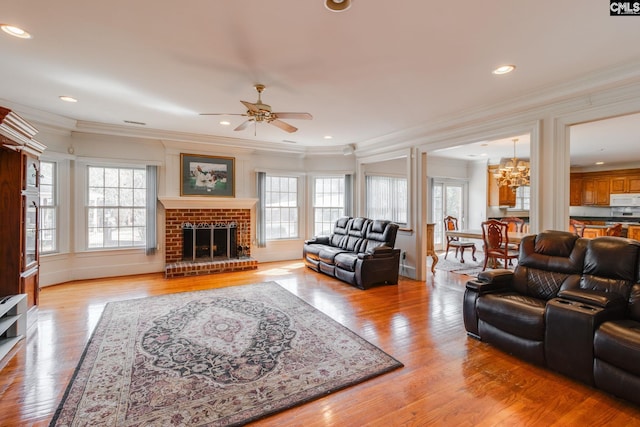 living area featuring light wood-type flooring, ornamental molding, plenty of natural light, and a fireplace