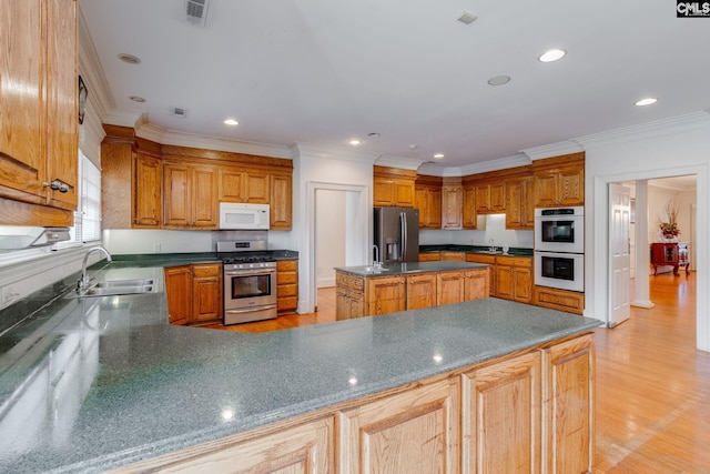 kitchen featuring stainless steel appliances, a sink, visible vents, light wood-style floors, and ornamental molding