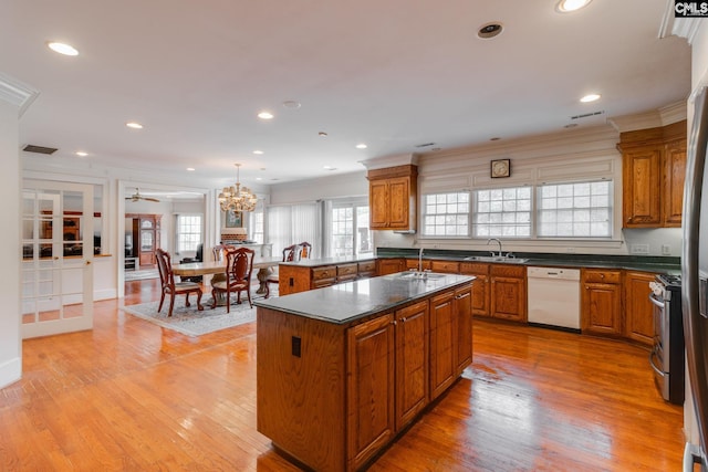 kitchen featuring light wood-type flooring, stainless steel gas range, white dishwasher, and brown cabinets