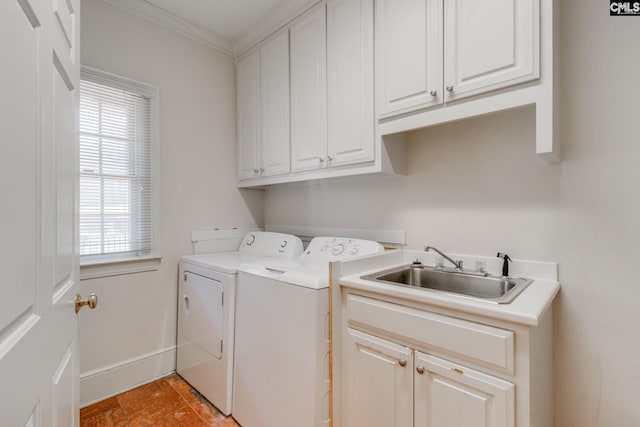 washroom featuring washing machine and dryer, a sink, baseboards, cabinet space, and crown molding