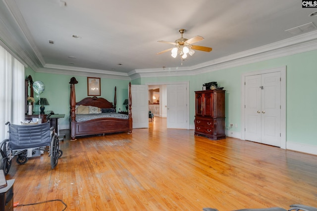 bedroom with crown molding, visible vents, light wood-style flooring, a ceiling fan, and baseboards