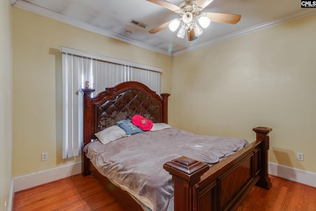 bedroom with ornamental molding, wood finished floors, visible vents, and baseboards