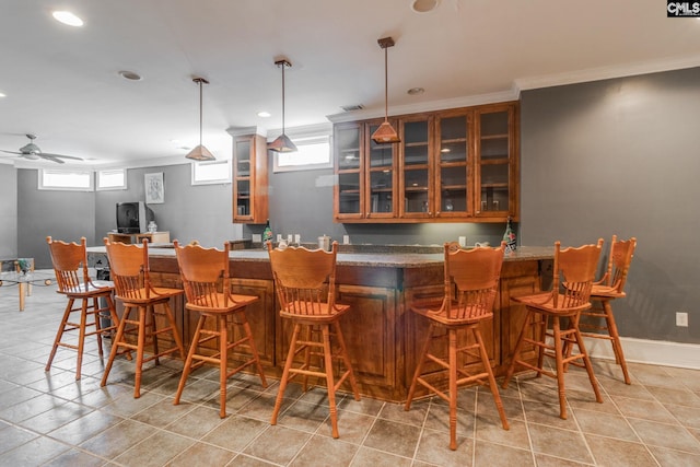 bar featuring baseboards, indoor bar, and crown molding