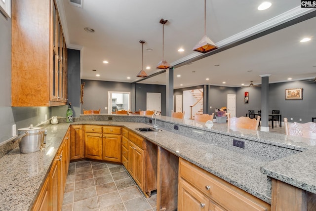 kitchen featuring light stone counters, crown molding, pendant lighting, a sink, and recessed lighting