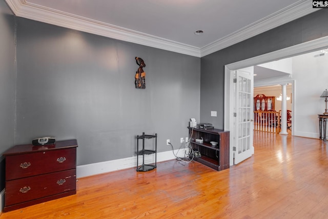 interior space featuring wood finished floors, baseboards, french doors, decorative columns, and crown molding