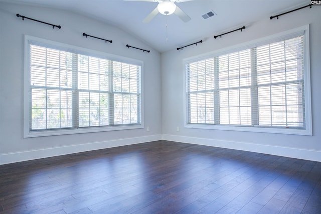 spare room featuring lofted ceiling, ceiling fan, visible vents, baseboards, and dark wood finished floors