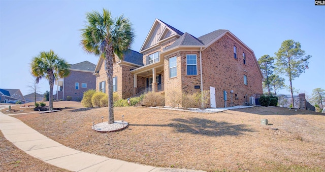 view of front facade with brick siding, fence, and central air condition unit