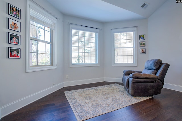 living area with dark wood-style flooring, visible vents, and baseboards