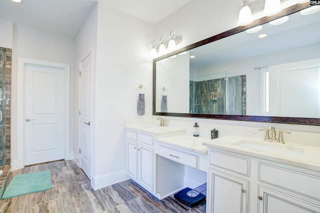 bathroom featuring double vanity, a stall shower, a sink, and baseboards