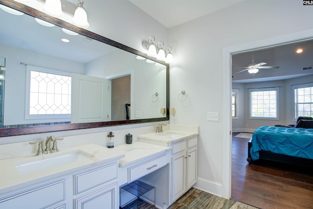 ensuite bathroom featuring connected bathroom, a sink, baseboards, and wood finished floors