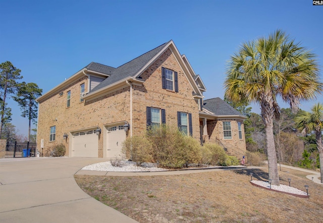 traditional-style house with an attached garage, brick siding, a shingled roof, fence, and concrete driveway